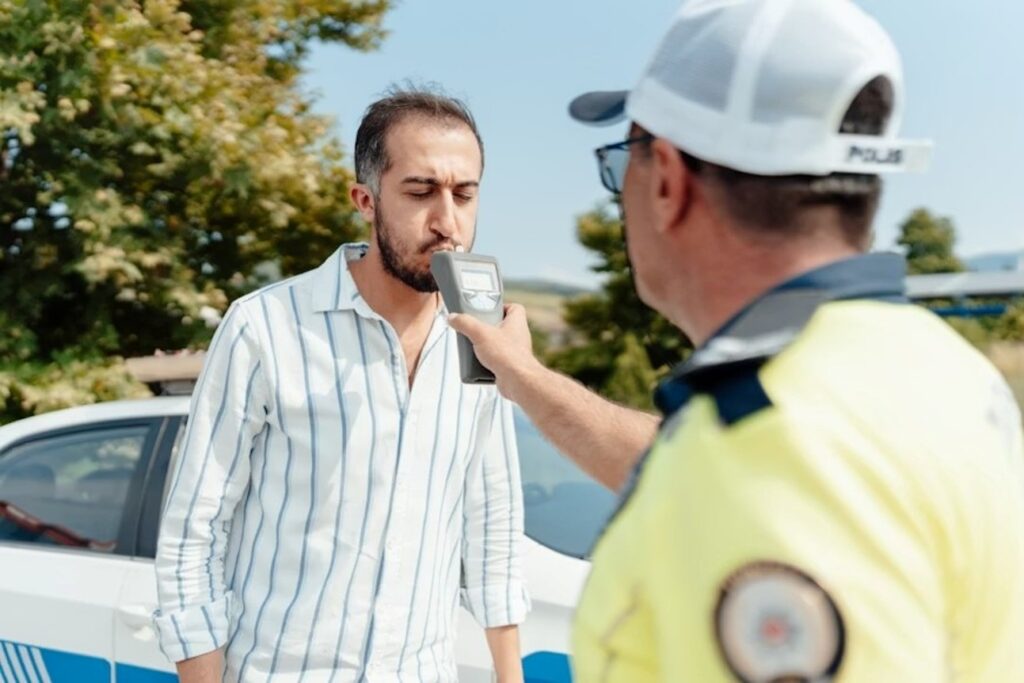 A driver taking a BAC test on a breathalyzer