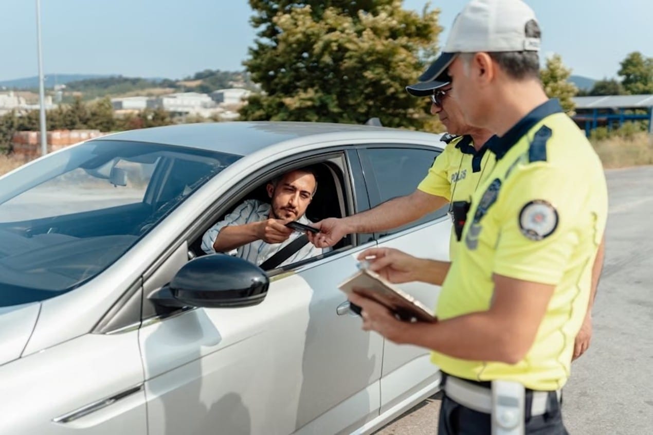 A man pulled over by traffic officers, handing over his license and registration.