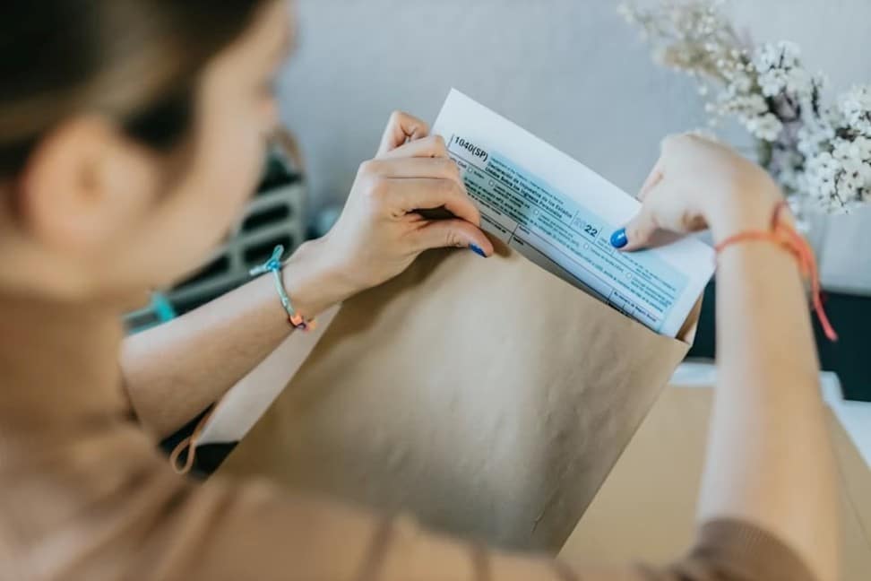 A person putting a document in a brown envelope for submission