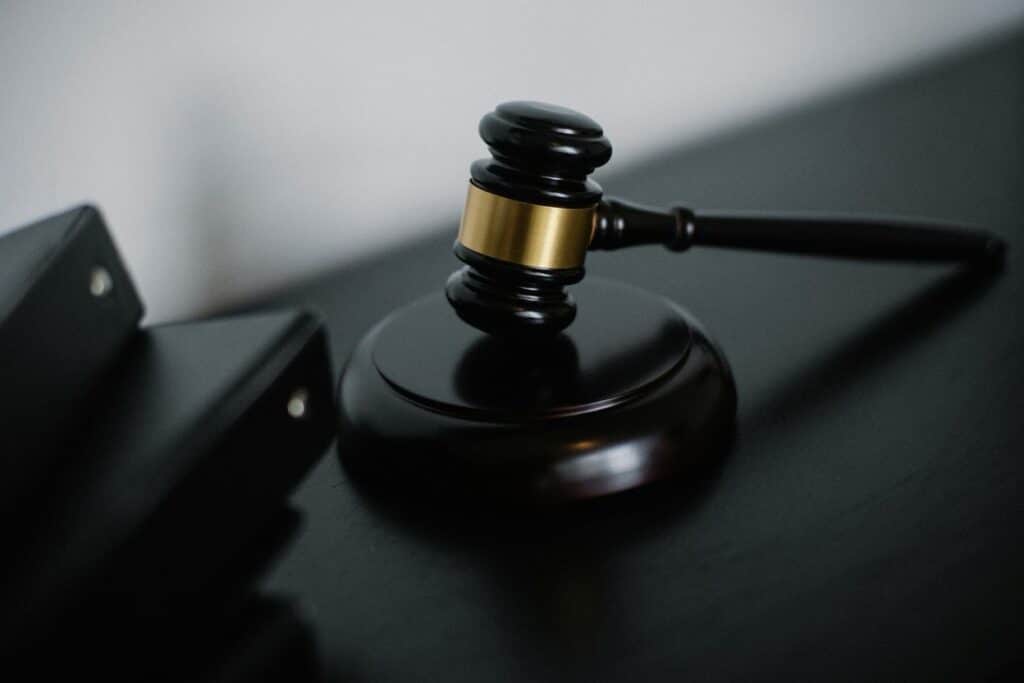 A dark wooden judge's gavel with a gold band resting on its sounding block on a courtroom desk