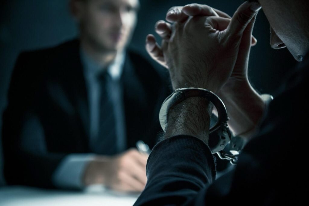 A person's handcuffed wrists during what appears to be a police interrogation