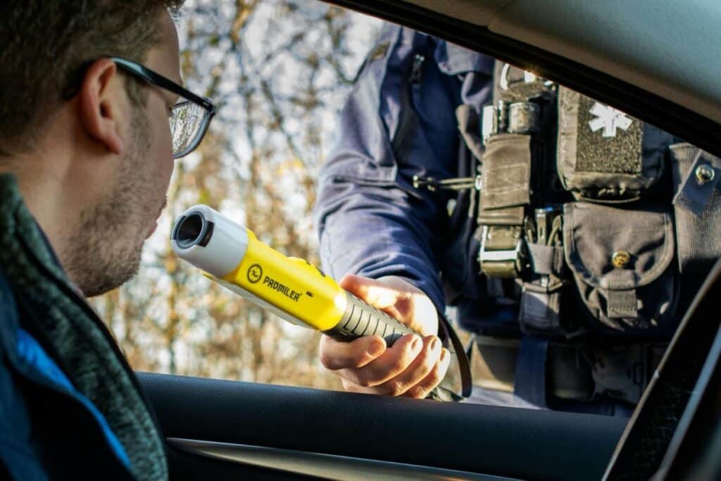 A police officer administers a breathalyzer test to a driver