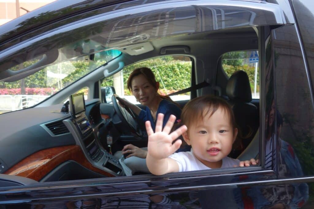 A woman in a car with a child who is pressing his hands against the car window