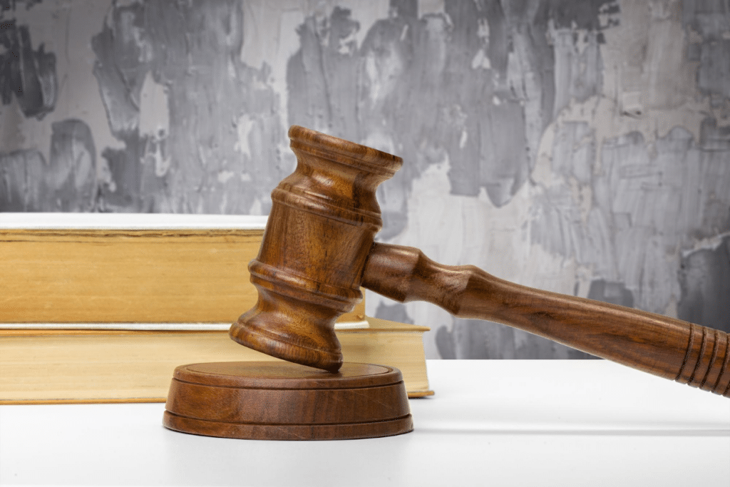 A wooden gavel resting on a sound block with a legal book in the background