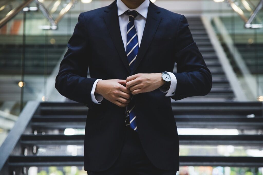 Attorney in a dark suit adjusting his jacket in a professional building