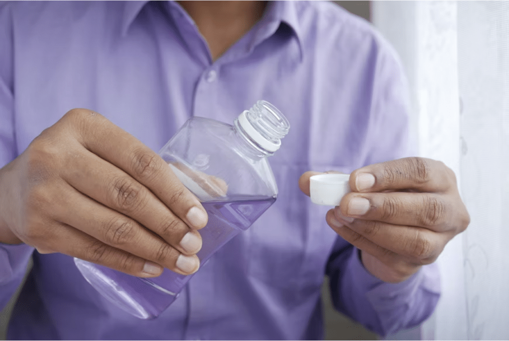 Man holding an open bottle of mouthwash