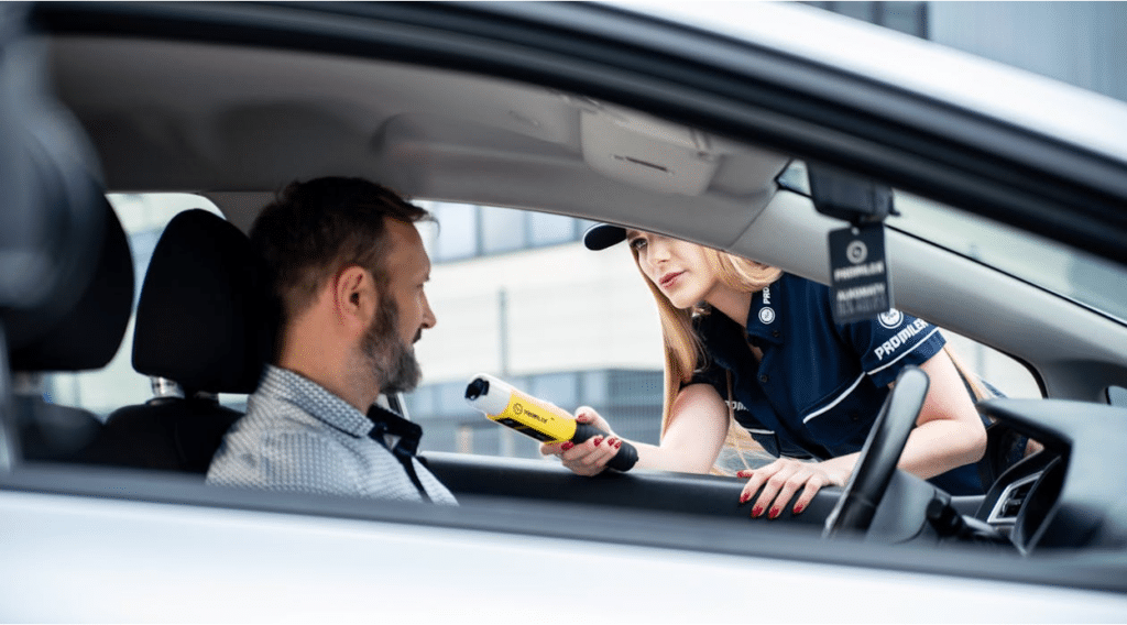 Officer administering a handheld breathalyzer test to a driver