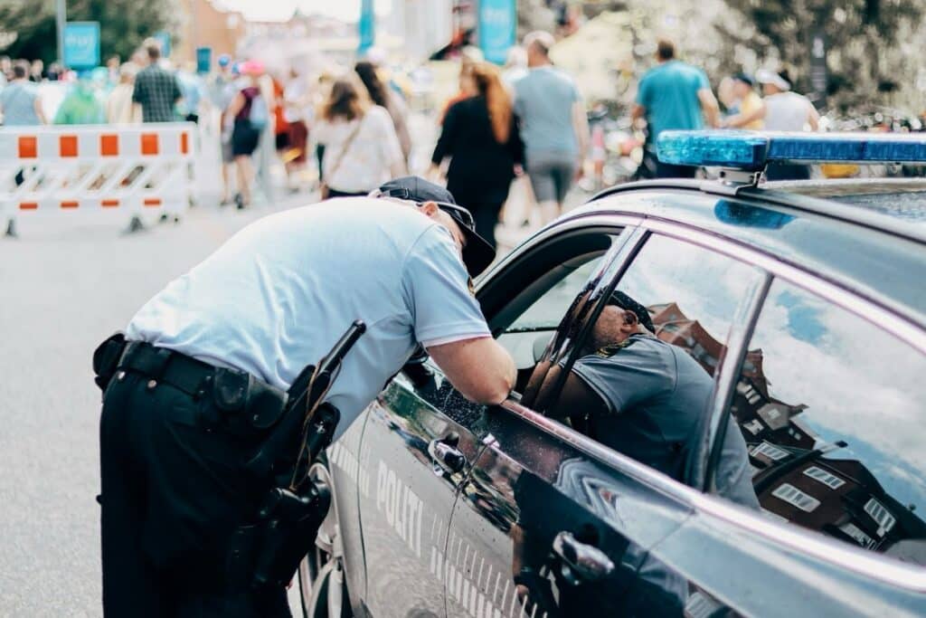 A police officer leaning into the window of a car.