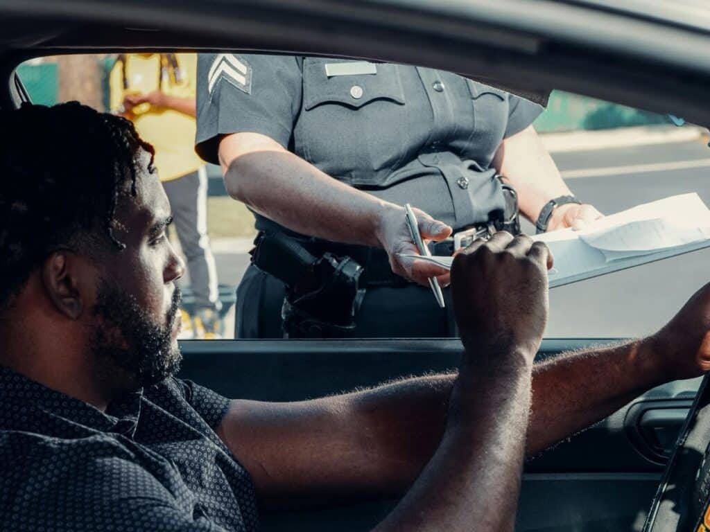 A police sergeant handing paperwork to a driver through a car window