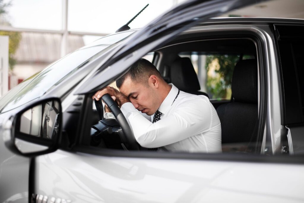 A tense and exhausted man slumped over the car's steering wheel.