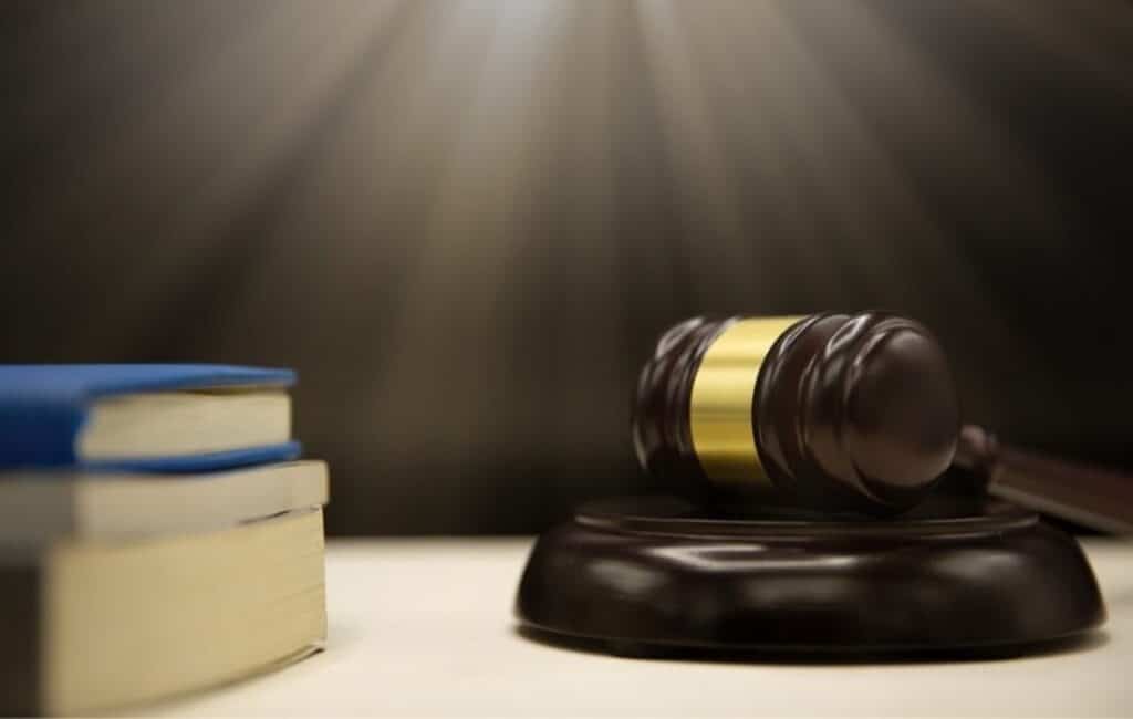 A wooden judge's gavel resting on its sound block beside stacked law books