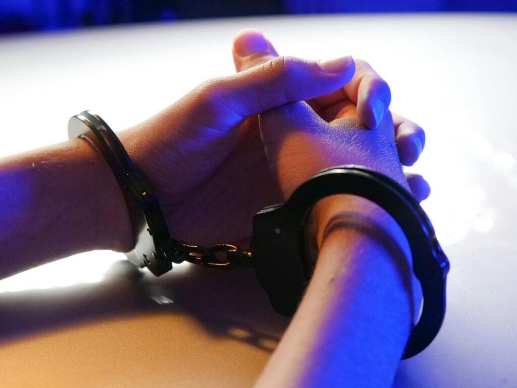 Clasped hands in metal handcuffs.