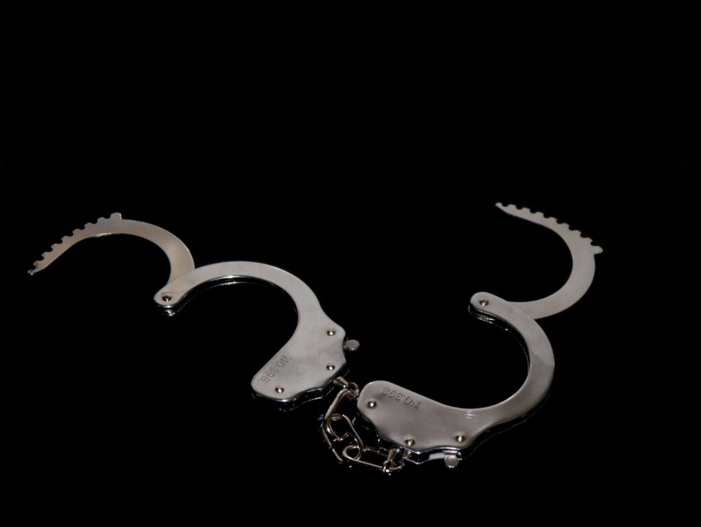Open chrome handcuffs against a black background representing a first DWI arrest in Texas.